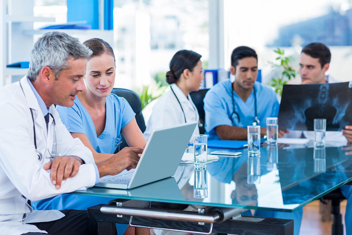 doctors sitting around a table with papers and laptops