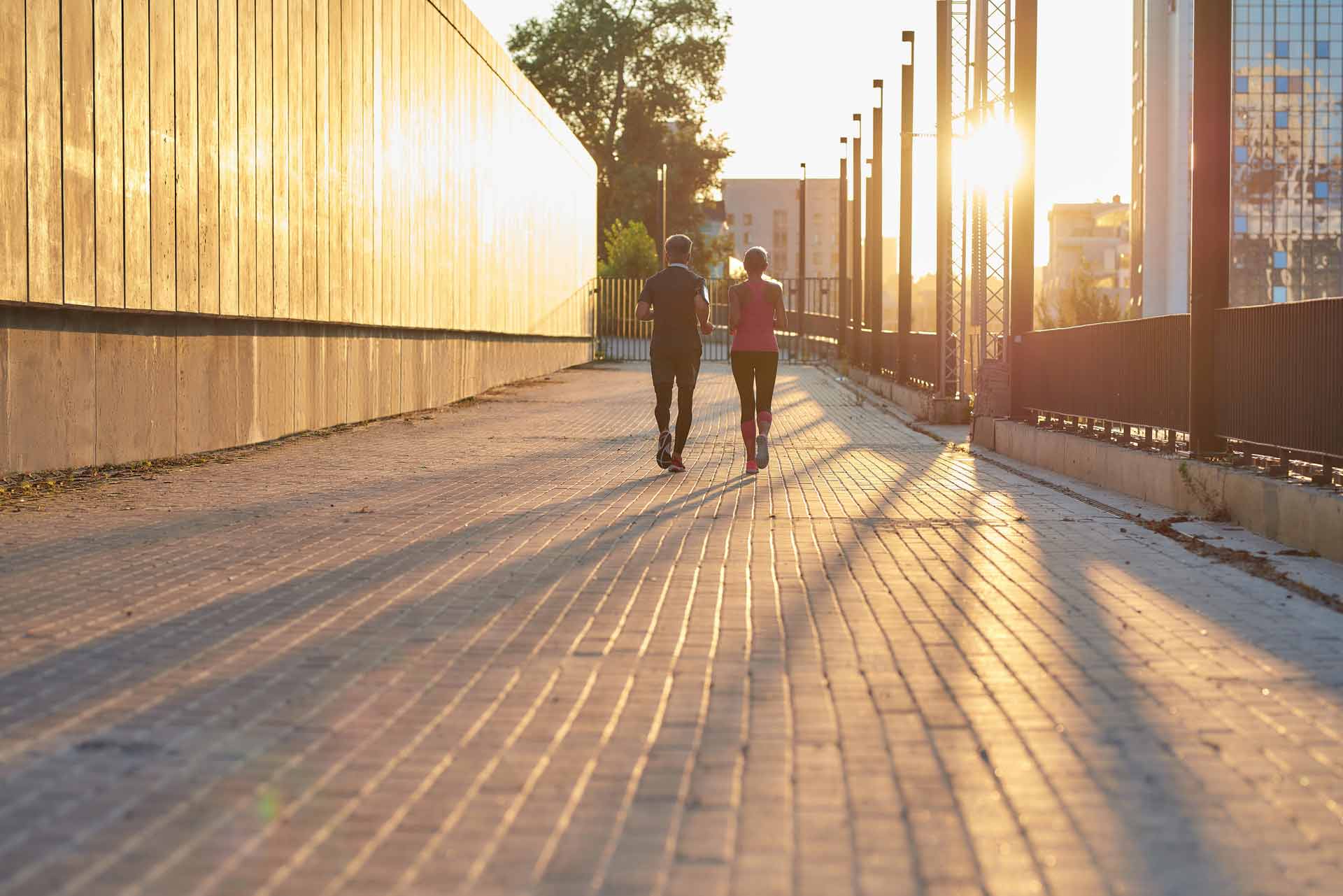 Back view of a couple in sport clothing walking through a city street on a sunny day